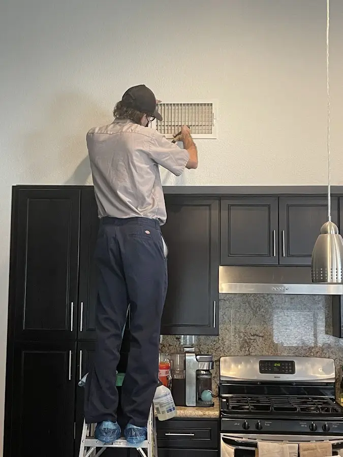 Technician inspecting an air vent during HVAC service in Webster